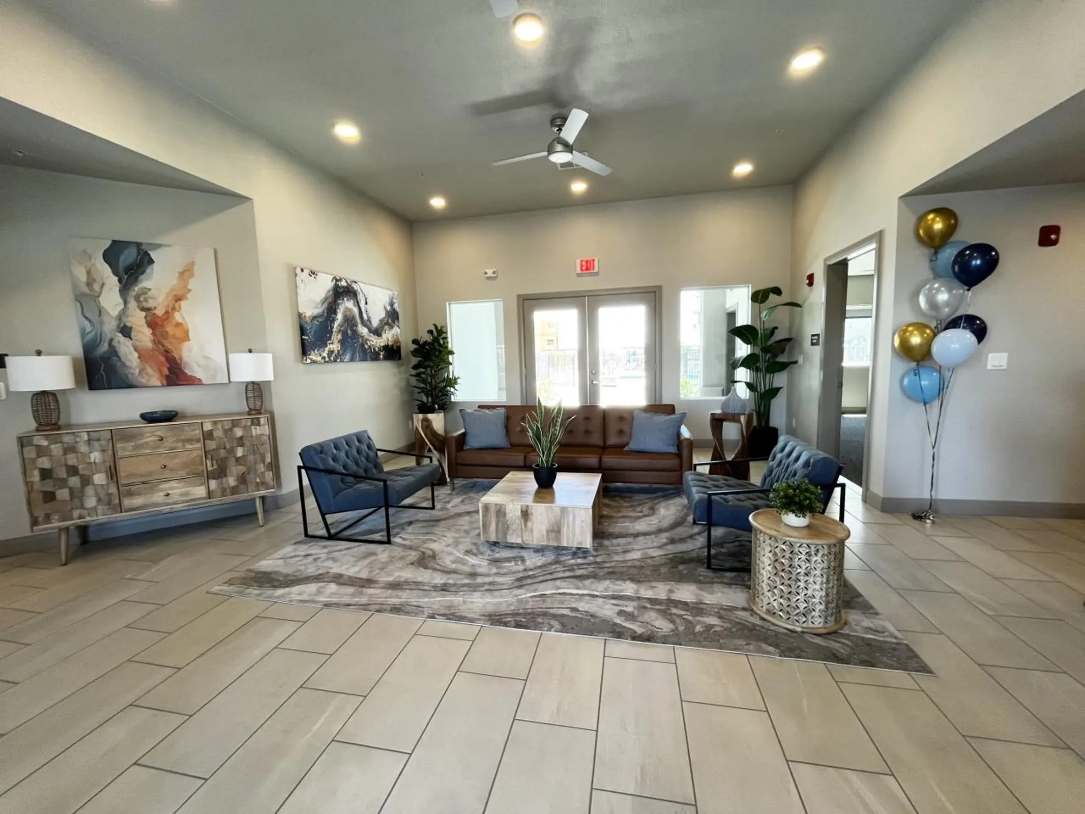 Furnished community lobby with blue chairs, a sofa and balloons.