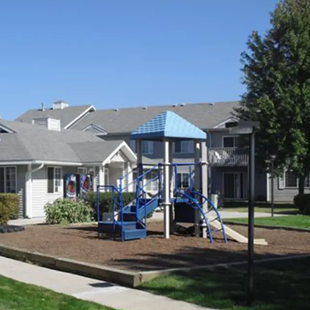 Playground Area Near Apartments Playground area with a blue play structure in front of residential buildings on a clear day.