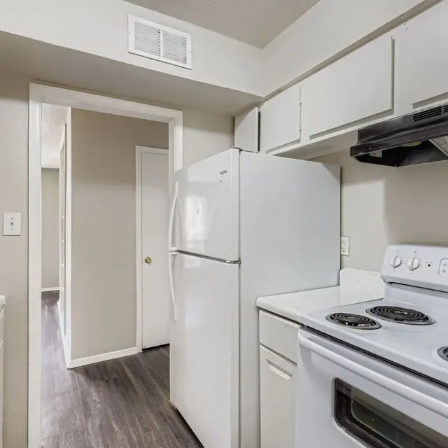A small kitchen featuring white appliances, including a refrigerator, stove, and microwave, with light gray walls and modern flooring.