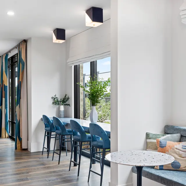 A bright and stylish living space featuring a mix of seating options, large windows, and contemporary decor.