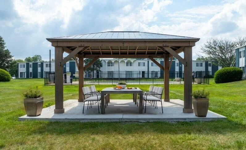 Outdoor Gazebo Dining Area An outdoor gazebo with a dining table and chairs on a grassy area.
