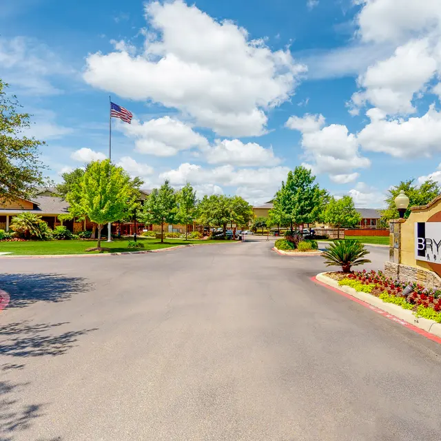 Entrance to Brynwood Community with manicured lawns and trees under a blue sky.