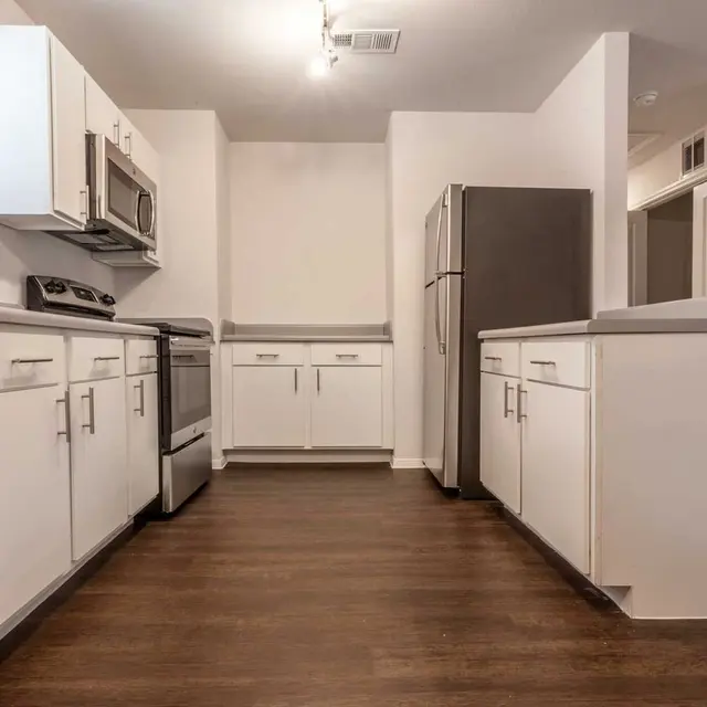 Interior view of a modern kitchen with white cabinets and stainless steel appliances.