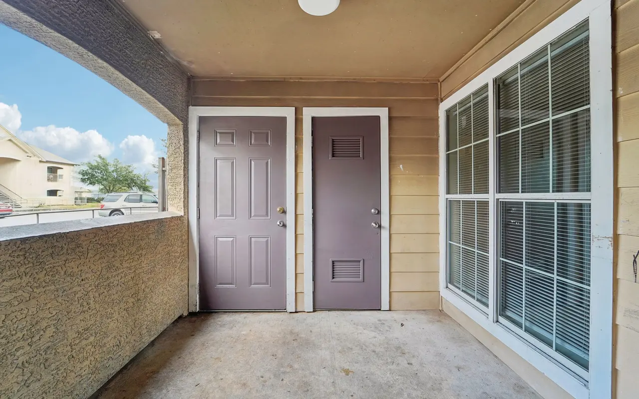 Entryway of an apartment with two doors and a view outside.