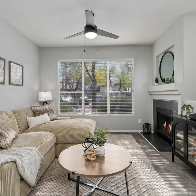 Cozy living room with natural light, ceiling fan, fireplace, and contemporary seating area at Bear Canyon Apartments