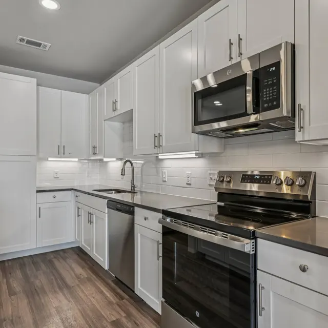 Modern Kitchen Design A modern kitchen featuring white cabinets and stainless steel appliances, with a sleek countertop and wooden flooring.