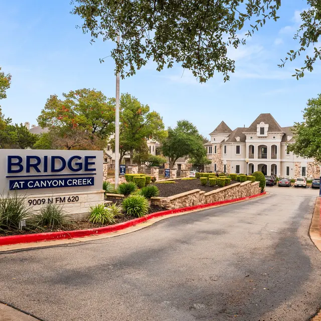 Entrance to Bridge at Canyon Creek, featuring a large sign and landscaped surroundings.