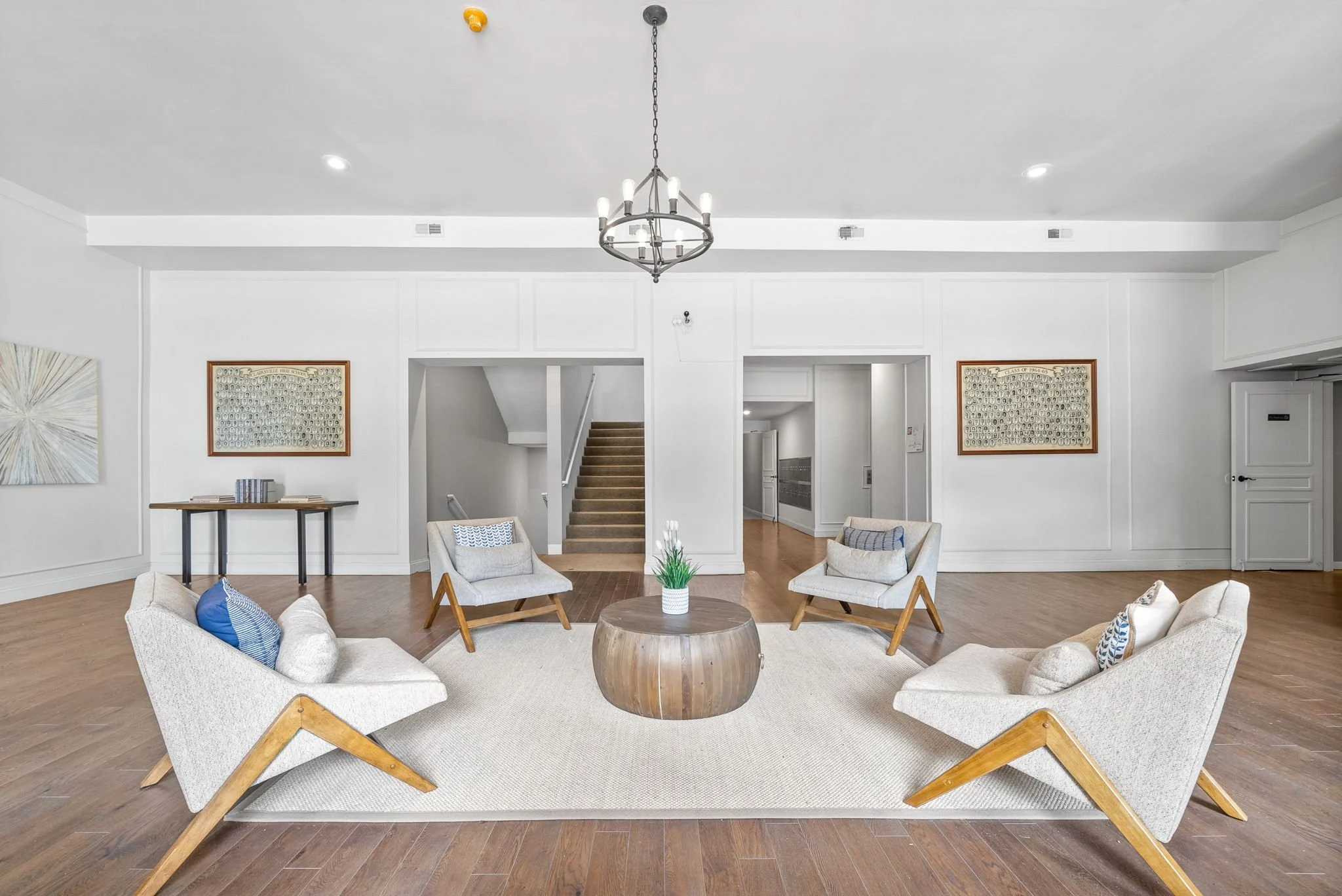 Modern Living Room Design A modern living room featuring stylish chairs and a round wooden coffee table on a rug, with artwork on the walls and a chandelier hanging from the ceiling.