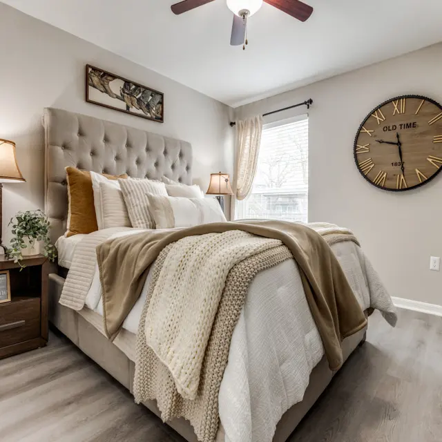 Cozy bedroom with a large bed, decorative pillows, a clock on the wall, and nightstands.