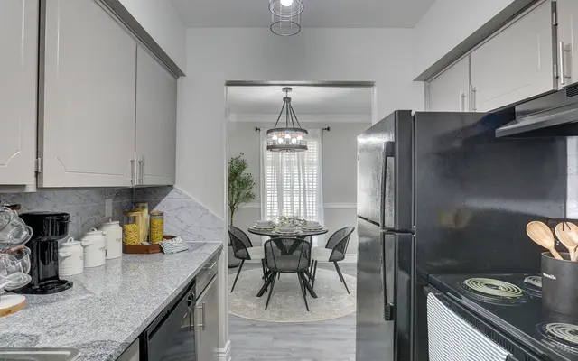 A modern kitchen with grey cabinets and a view into a dining area featuring a round table and chairs.