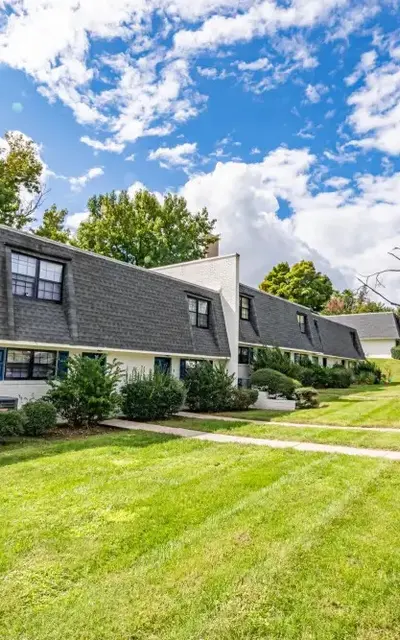 Exterior view of a two-story apartment complex with a grassy lawn and trees