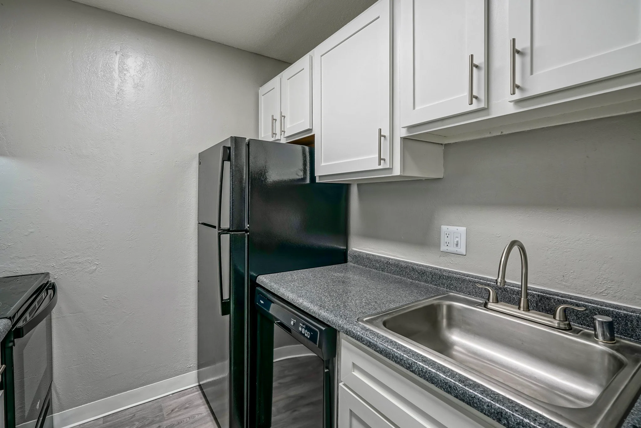 Modern Kitchen Interior A modern kitchen featuring white cabinetry, a black refrigerator, and a stainless steel sink with a countertop.