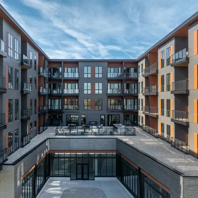 A modern apartment complex with balconies and large windows, featuring an open courtyard area.