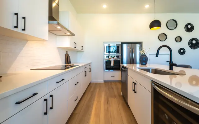 Modern kitchen featuring white cabinetry, stainless steel appliances, and wooden flooring.