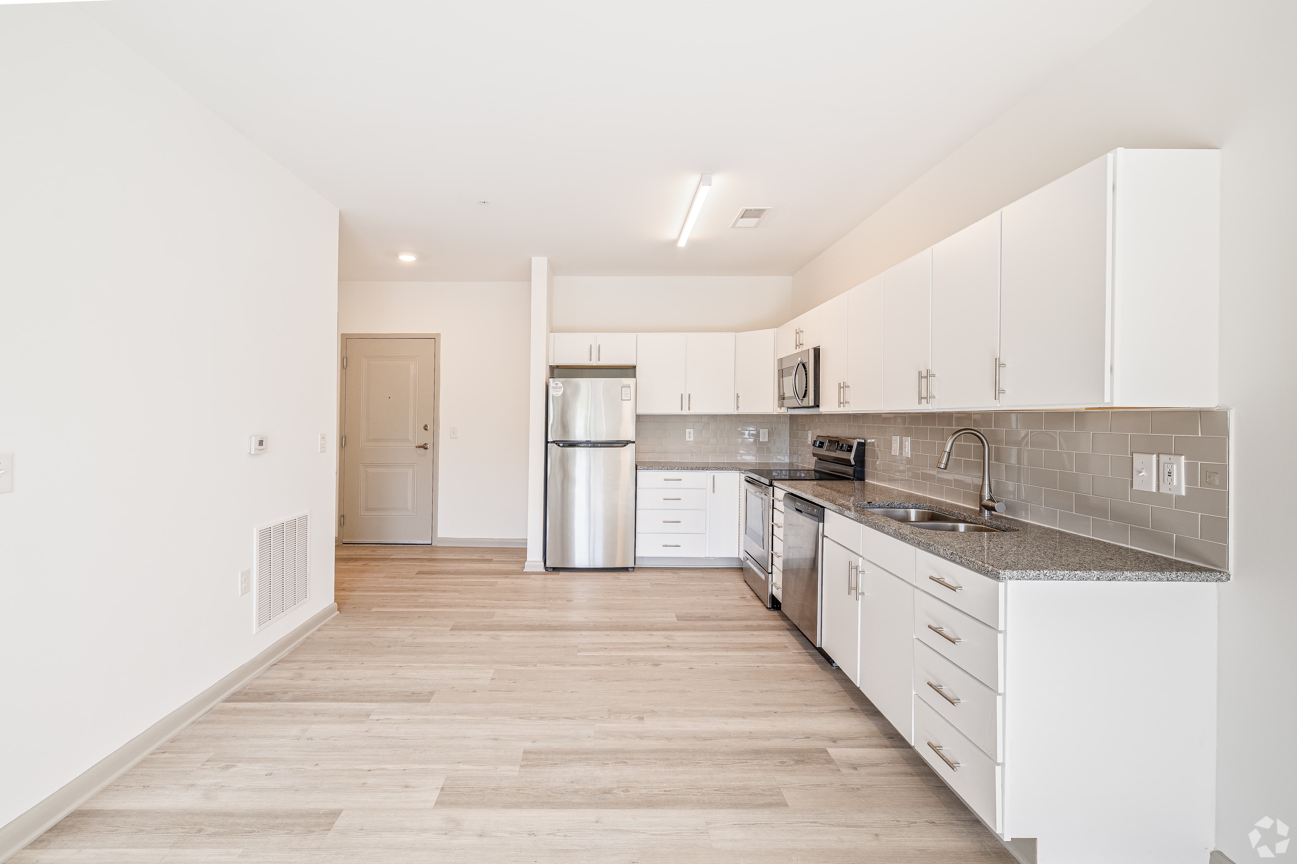 Modern Kitchen Design A modern kitchen with white cabinets, stainless steel appliances, and a light-colored wooden floor.