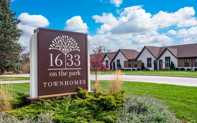 Sign for 1633 on the Park Townhomes with well-maintained grass and landscaped area in front of the building.