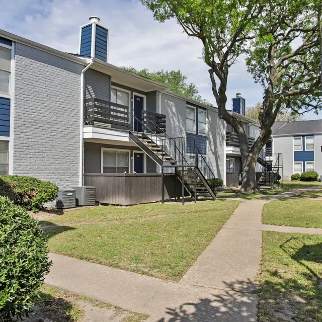 Apartment Complex Exterior A view of an apartment complex featuring two-story buildings, green grass, and well-maintained shrubs.