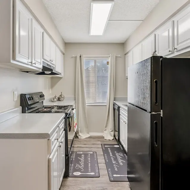 A modern kitchen featuring white cabinetry, black appliances, and natural light from a window.