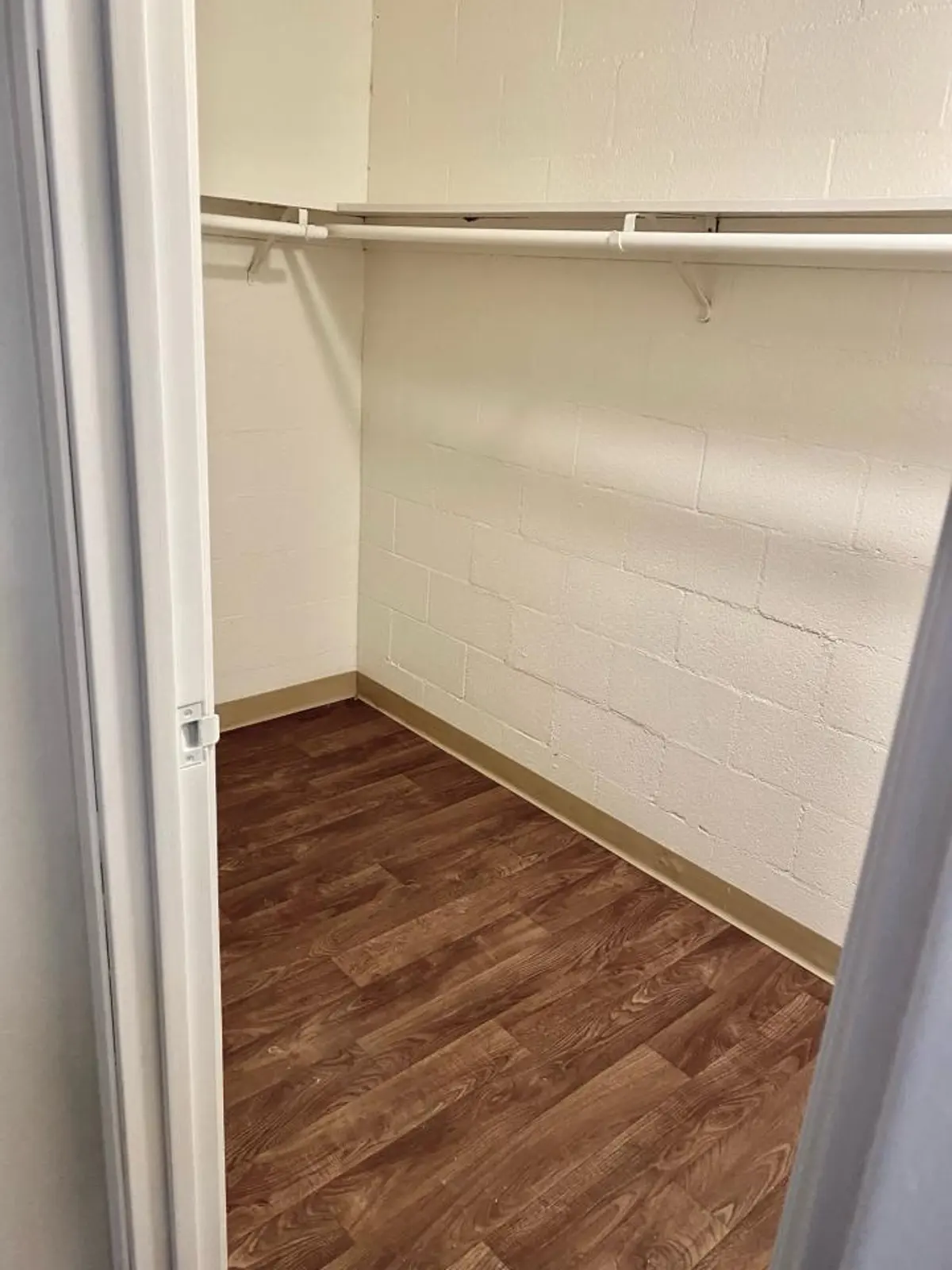 Walk-in closet with a hanging rail and upper shelf.