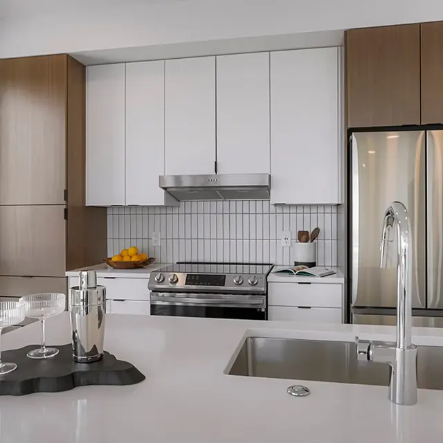 A modern kitchen featuring a blend of light and dark cabinets, stainless steel appliances, a sleek design, and minimalistic décor.