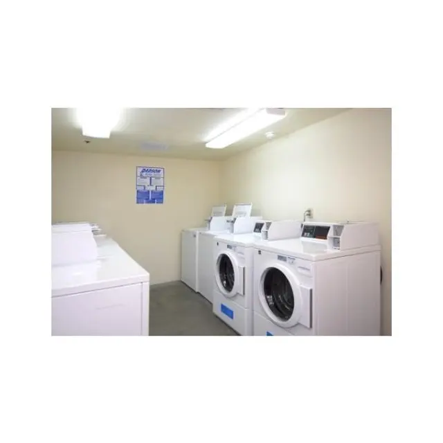 Laundry Room Interior A clean and organized laundry room featuring several washing machines and dryers.