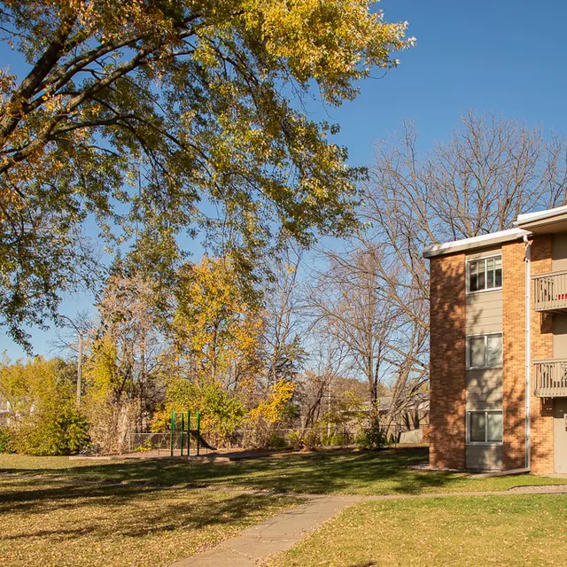 A neighborhood scene showcasing an apartment building surrounded by trees in autumn foliage.
