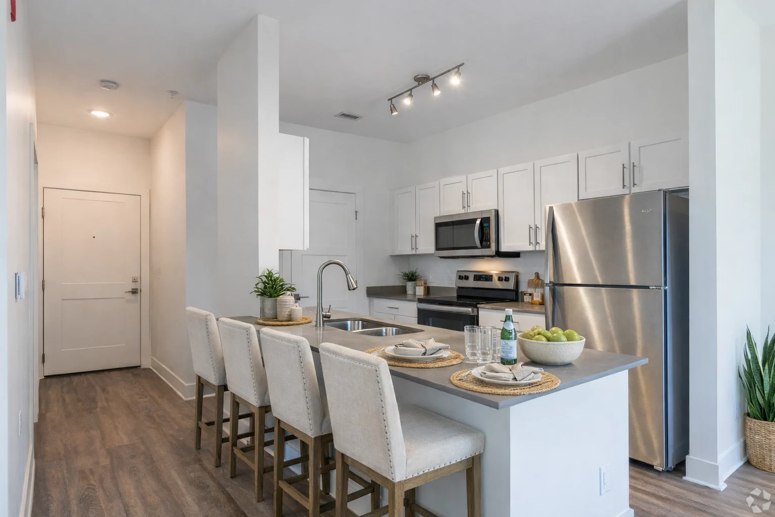 Contemporary Kitchen Design A modern kitchen featuring a large island with four bar stools, stainless steel appliances, and white cabinetry. The design is contemporary with clean lines and natural light.