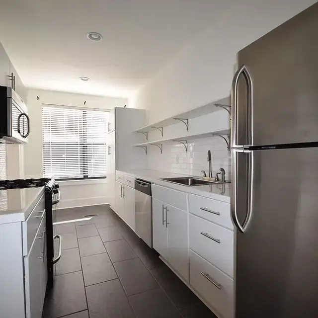 A modern kitchen featuring stainless steel appliances, white cabinetry, and a tiled floor.