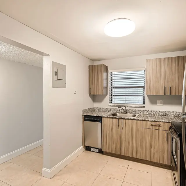 A modern kitchen featuring stainless steel appliances, wooden cabinets, and gray walls with tiled flooring.