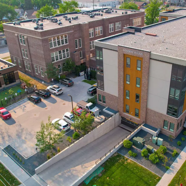 Aerial view of Woodrow Apartments in Fargo, ND, featuring a historic brick school building next to a modern apartment structure with adjacent parking.