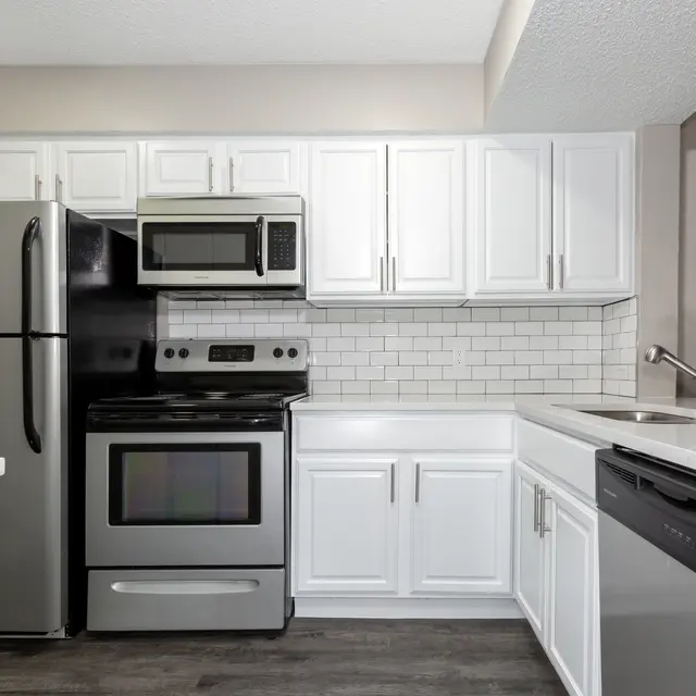 A modern kitchen featuring stainless steel appliances, white cabinetry, and a gray countertop.