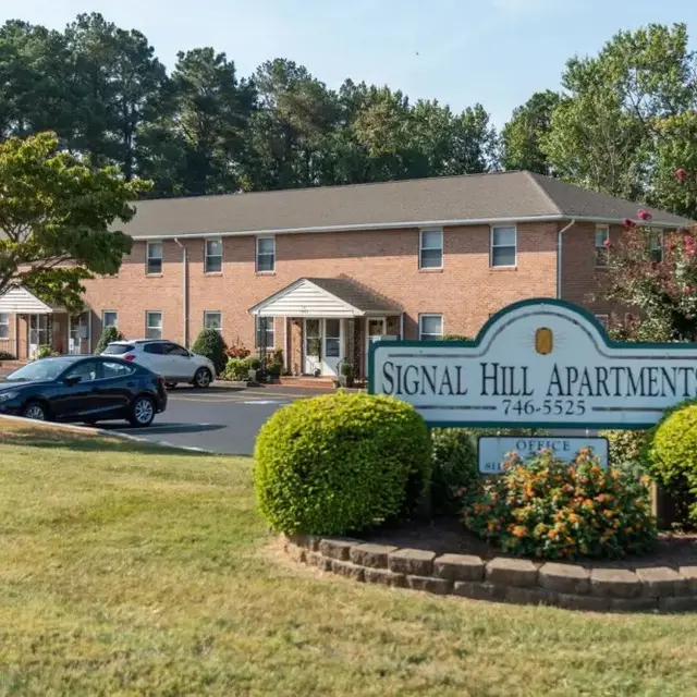 View of Signal Hill Apartments with landscaped surroundings and parking area.