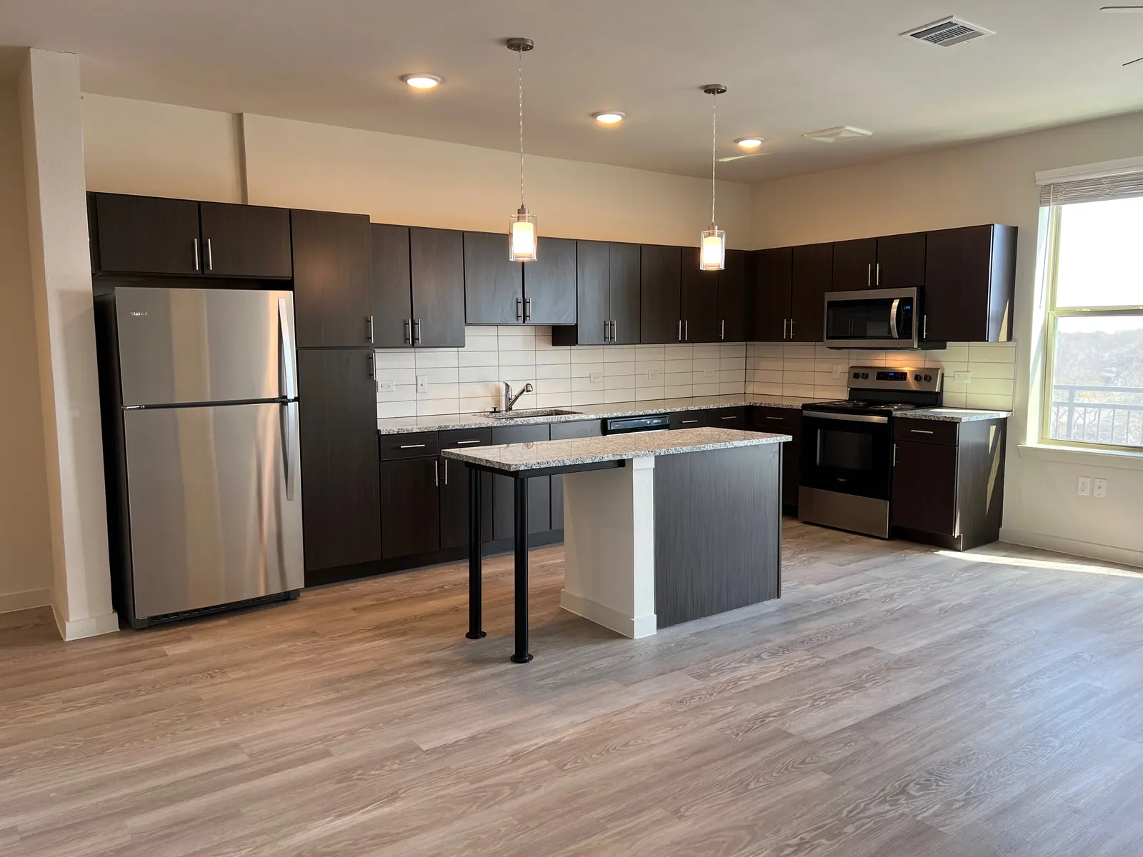 Contemporary Kitchen Interior A modern kitchen featuring dark wooden cabinets, stainless steel appliances, and a central island with a light-colored countertop.