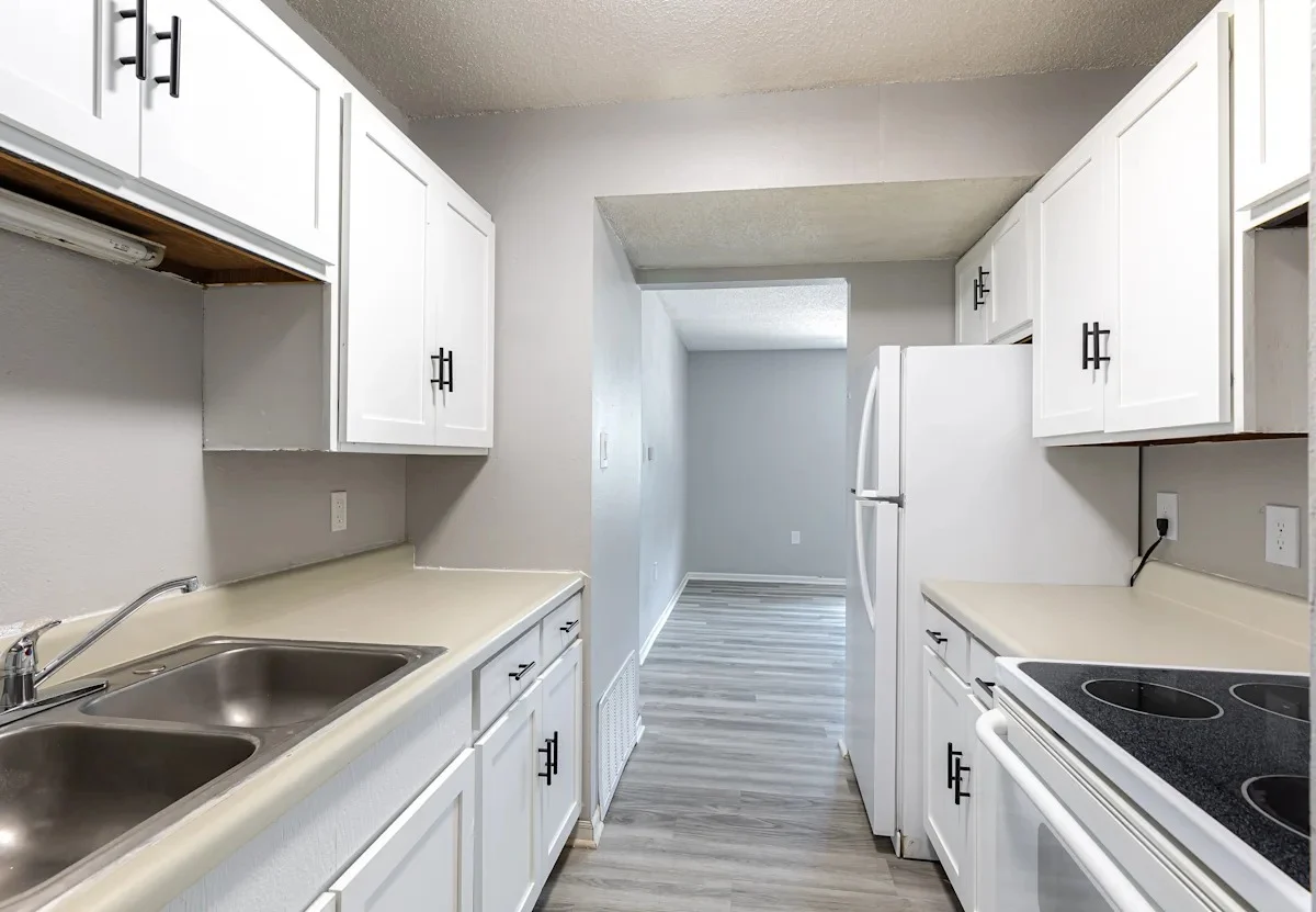 A modern kitchen featuring white cabinets, a double sink, and a stove in a clean design.