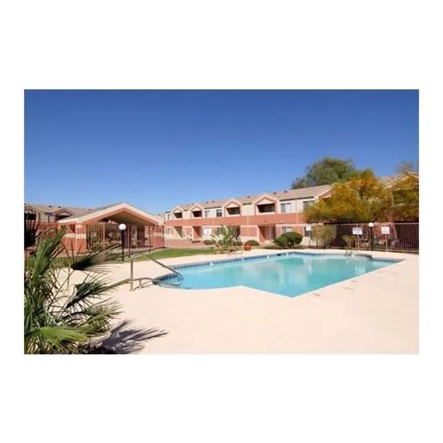A bright outdoor swimming pool surrounded by a patio area and residential buildings in the background.