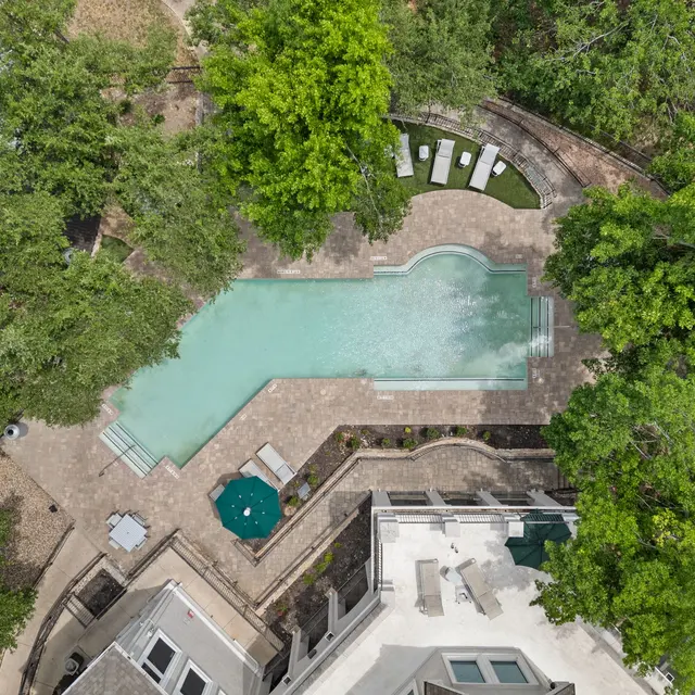 An aerial view of a landscaped area featuring a swimming pool surrounded by trees and lounge chairs.