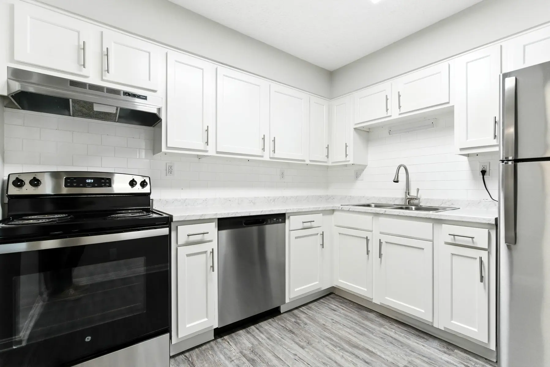 Modern kitchen featuring white cabinetry, stainless steel appliances, and a clean, minimalist design with a light color palette.
