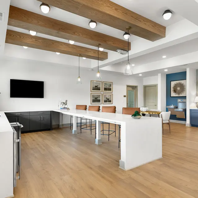 Bright modern kitchen space featuring a large island, wooden beams, and contemporary furnishings.