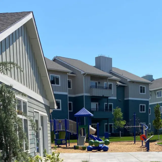 Canyon Terrace View of an apartment complex featuring a playground area, green grass, and blue skies.