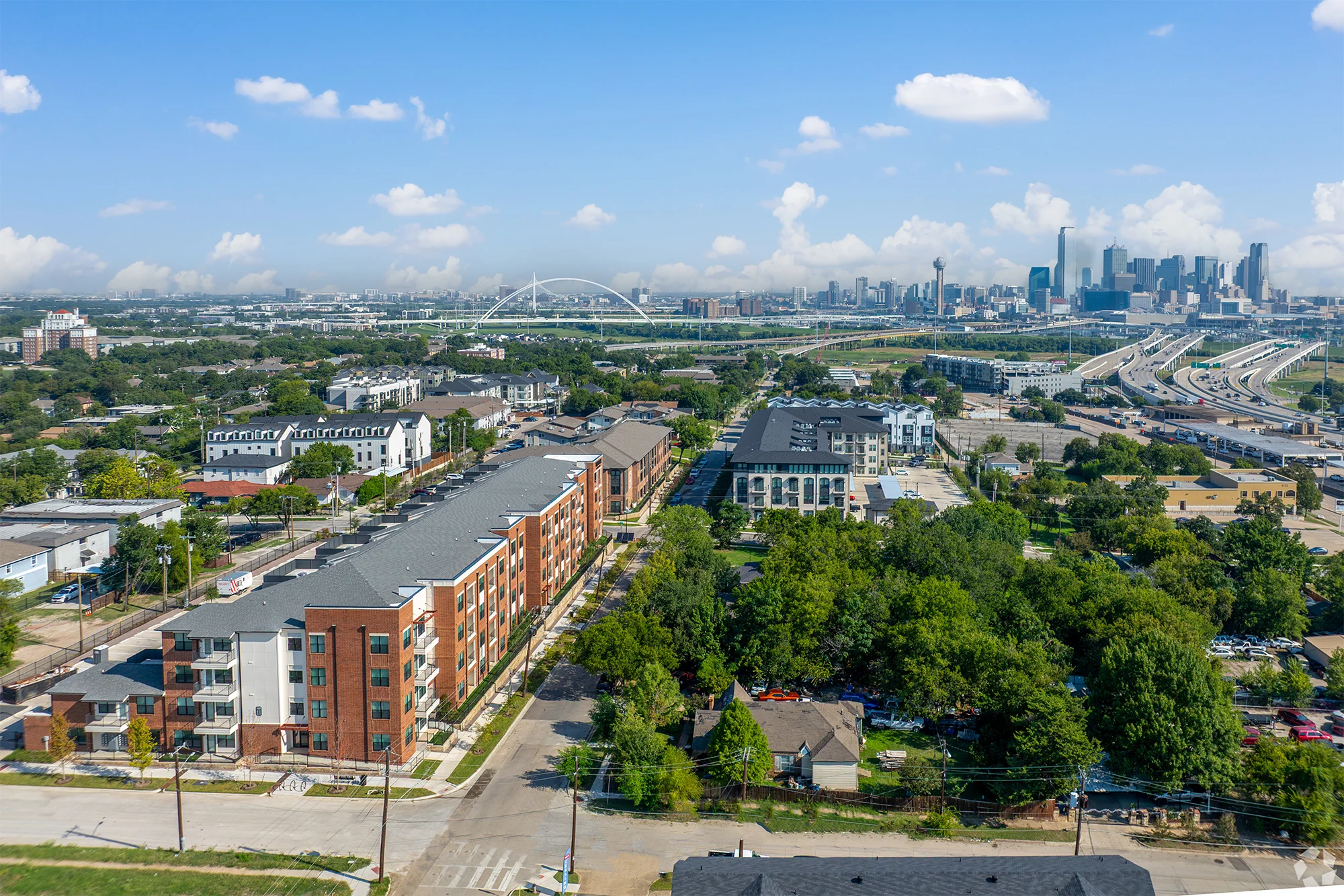 Aerial View of Houston's Urban Landscape Aerial view of residential buildings, green trees, and a distant city skyline with clouds.