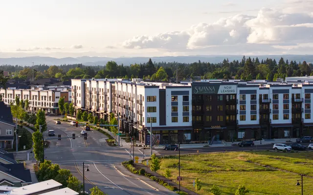 Modern Apartment Complex at Sunset Aerial view of a modern apartment complex located on a street intersection, featuring multiple floors and greenery surrounding the building.