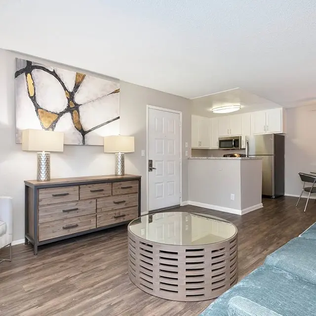 A modern living room with a comfortable teal sofa, a round coffee table, and contemporary decor including lamps and artwork on the walls.