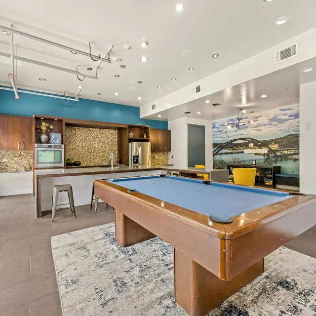 Modern billiard area with a pool table, kitchen space, and colorful seating.