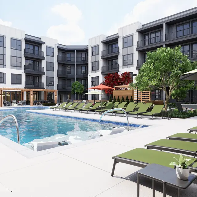 A modern swimming pool area surrounded by green lounge chairs and landscaped trees, with multi-storied apartments in the background.