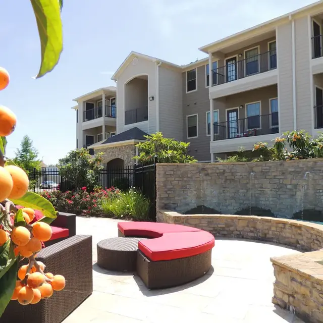 Outdoor pool area with seating and flowering plants.