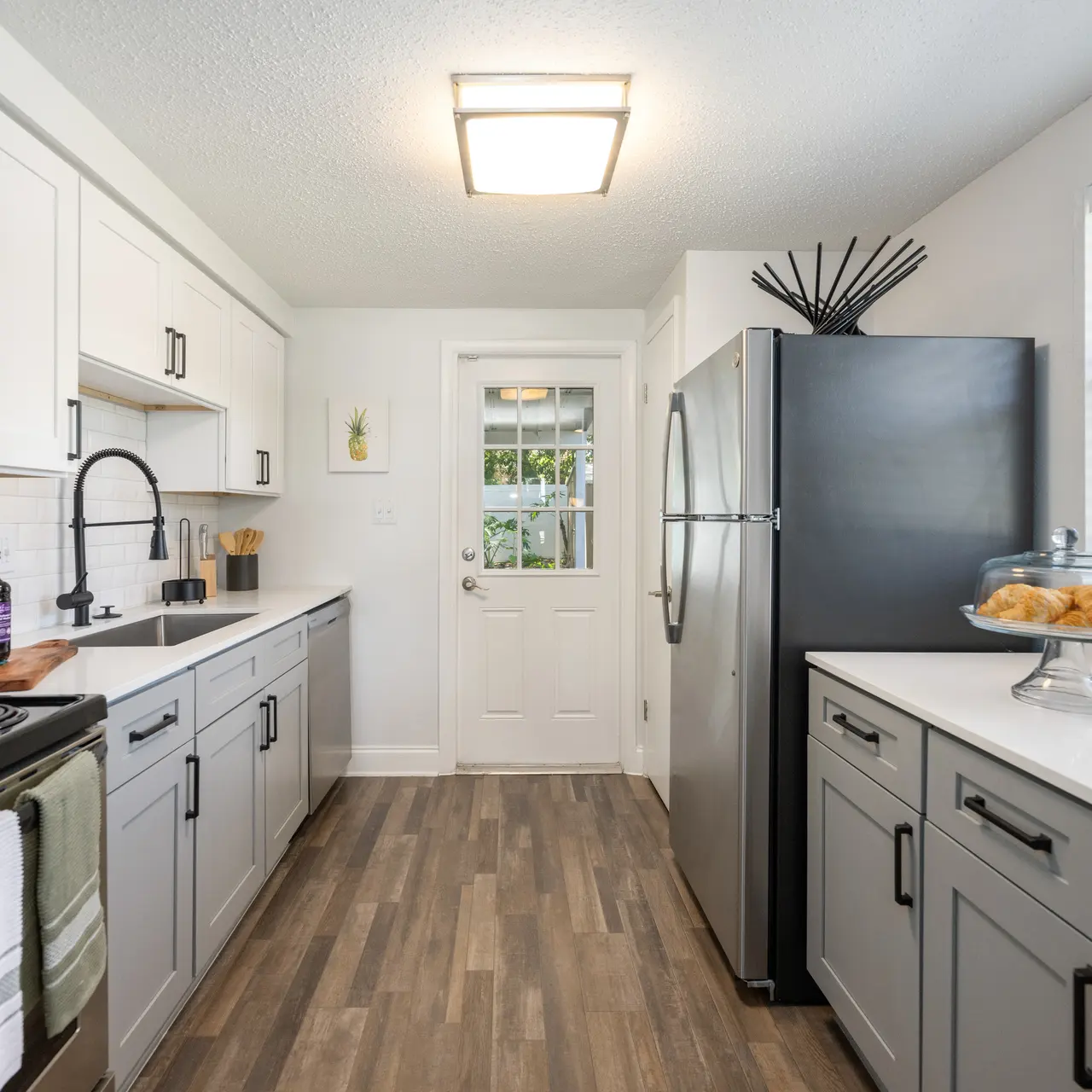 Bright and modern kitchen featuring white cabinets, stainless steel appliances, and a large window for natural light.