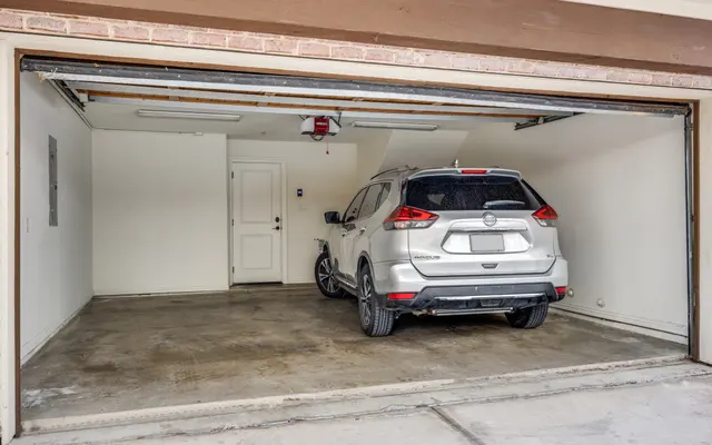 Spacious Garage with SUV An empty garage with a silver SUV parked inside and a door leading to an adjacent area.