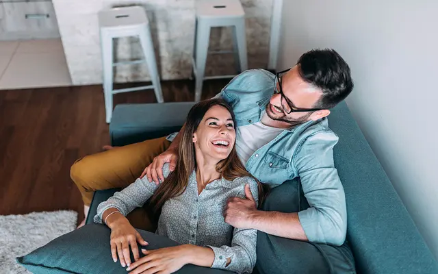 Couple Enjoying Time Together A happy couple sitting together on a couch, smiling and enjoying each other's company in a cozy living space.