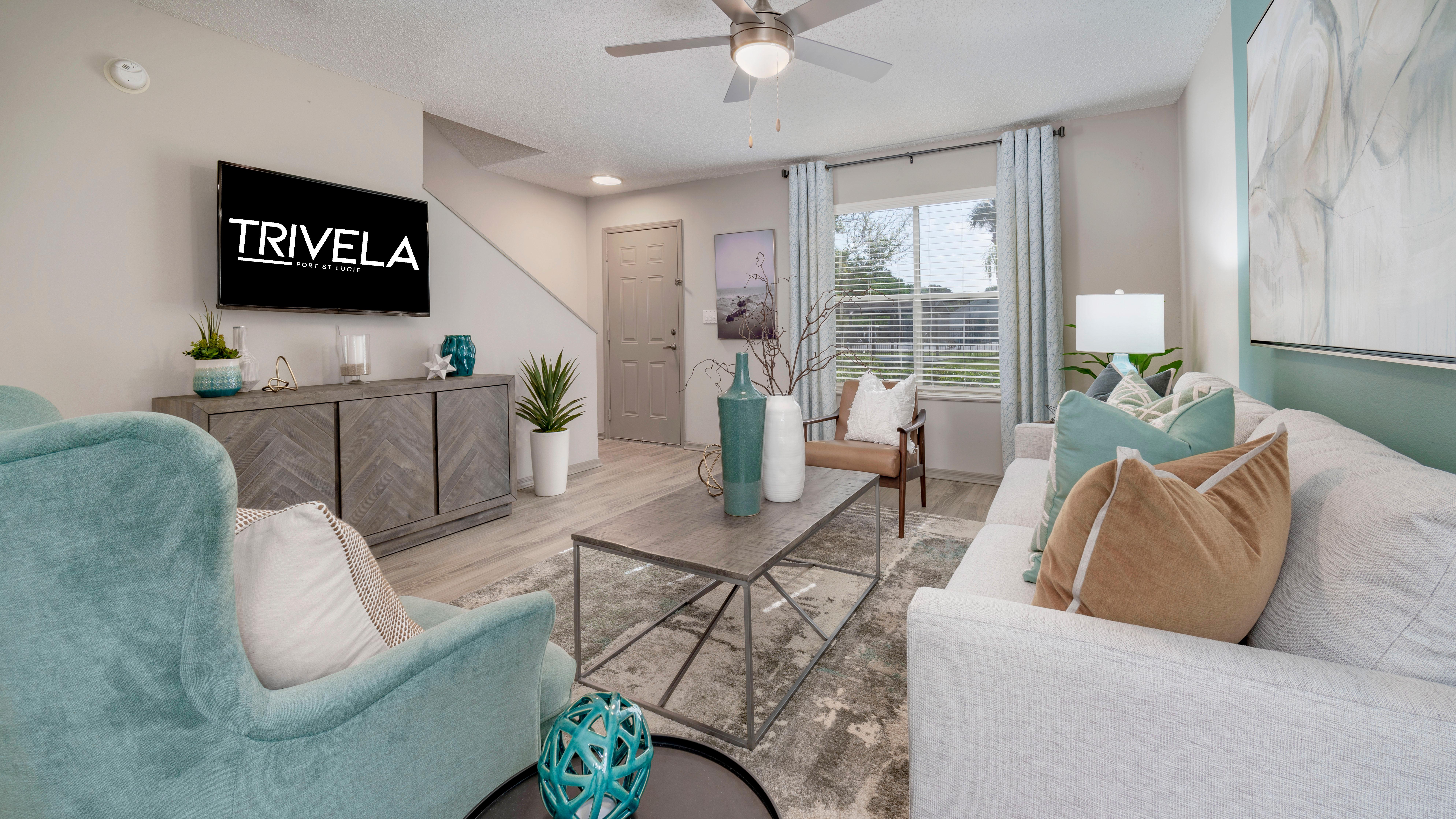 Stylish living room with modern furnishings, a coffee table, and a television on the wall.