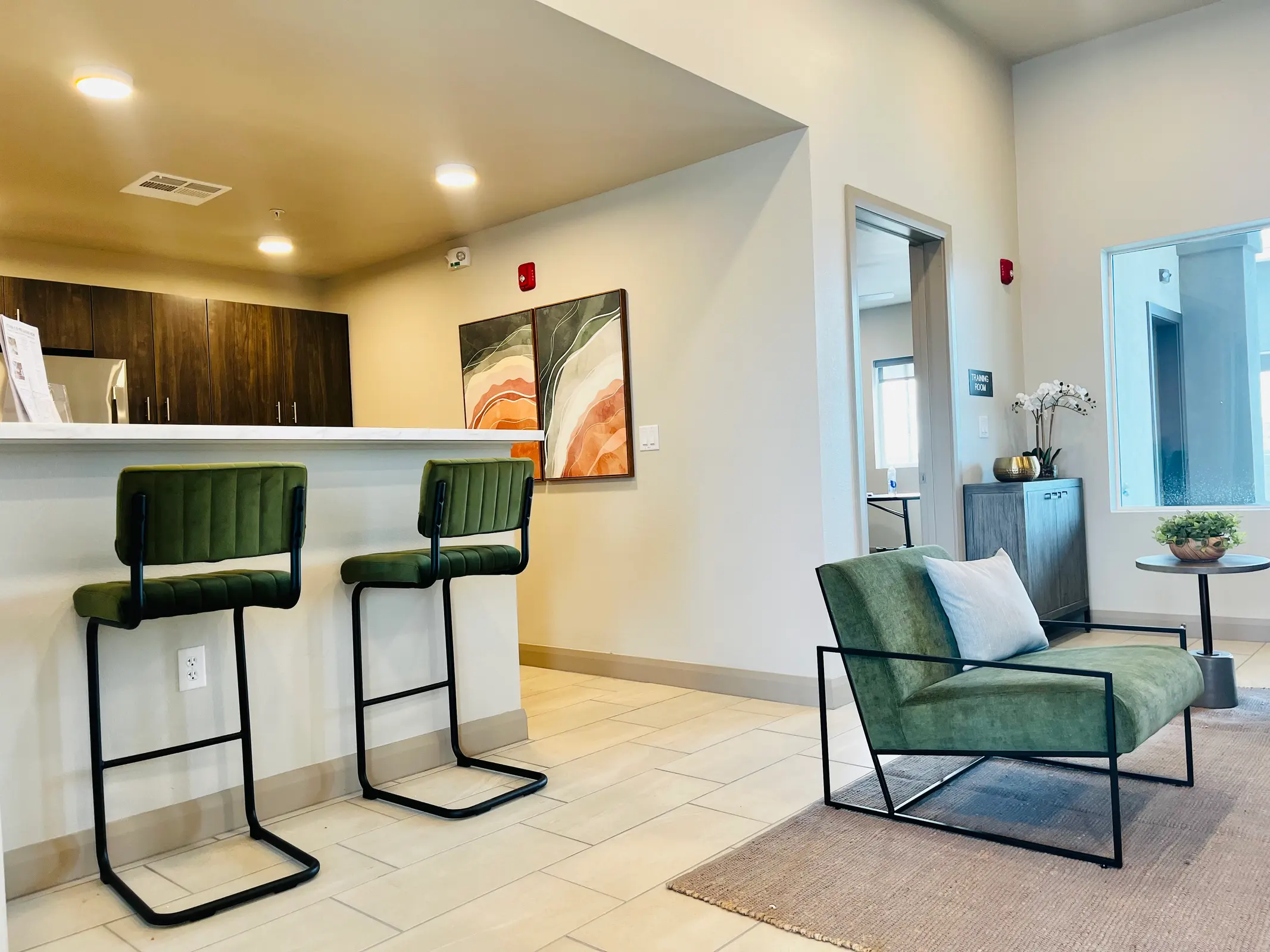 Kitchen counter with two green stools beside a lounge chair.